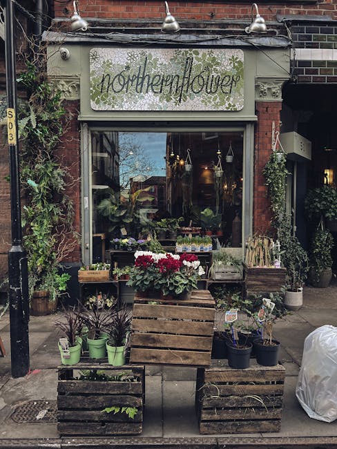 The exterior of a flower shop named 'northernflower' located on a brick building façade, with a white sign displaying the shop's name and decorative greenery. Outside, an arrangement of potted plants