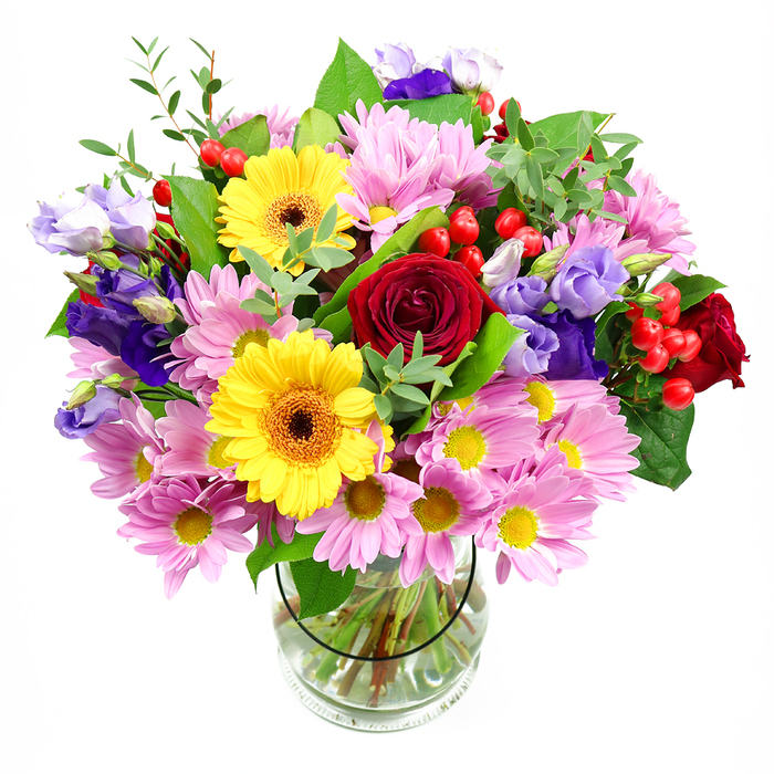 In this image, a tall, generously filled bouquet seems to float against a crisp white background, every bloom clearly visible in a simple clear glass vase. At the very centre, a cluster of deep red roses forms the emotional anchor of the design, their lush, velvety petals curling inward and outward in classic spirals that speak of romance and heartfelt affection. Flanking the roses are two golden yellow gerbera daisies with distinct brown-orange centres, their broad, radiating petals giving the arrangement a bright, modern lift, like a splash of sunshine breaking through clouds above the hills near Crystal Palace Park. Surrounding this central core, layers of soft pink and lavender daisies or chrysanthemums fan out, each dotted with small yellow eyes that subtly echo the warmth of the gerberas. These blooms add generous volume, creating a cushion of gentle colour that softens the stronger tones. Rising gracefully among them, slender stems of purple and lilac lisianthus introduce a cooler note; their bell-shaped flowers and ruffled edges provide elegant movement, drawing the eye upward and adding depth to the structure. Here and there, firm clusters of glossy red hypericum berries appear between leaves and petals, their rounded shape and vibrant colour adding texture and a lively, berry-bright accent. A rich mix of foliage-some leaves broad and dark, others fine and pale green-frames the bouquet and fills any gaps, giving it a full, expertly finished look that feels both polished and natural, as though freshly arranged in a local Upper Norwood studio just off the high street. The transparent vase reveals the carefully cut stems and clear water inside, grounding the exuberant top with a sense of order and craftsmanship. This bouquet radiates quiet celebration and thoughtful intention, ideal as a striking centrepiece for a gathering in SE19, a joyful birthday surprise, or a simple way to bring colour and life into a home.